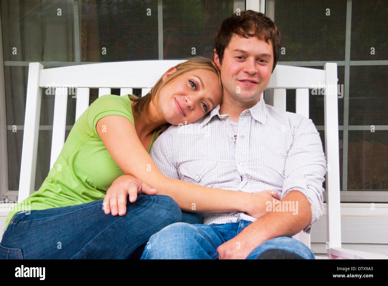 Engaged couple spending time together sitting on a porch with a white ...
