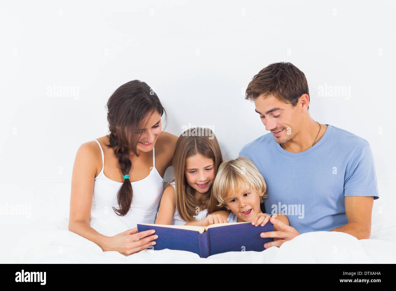 Family sitting with a storybook on the bed Stock Photo