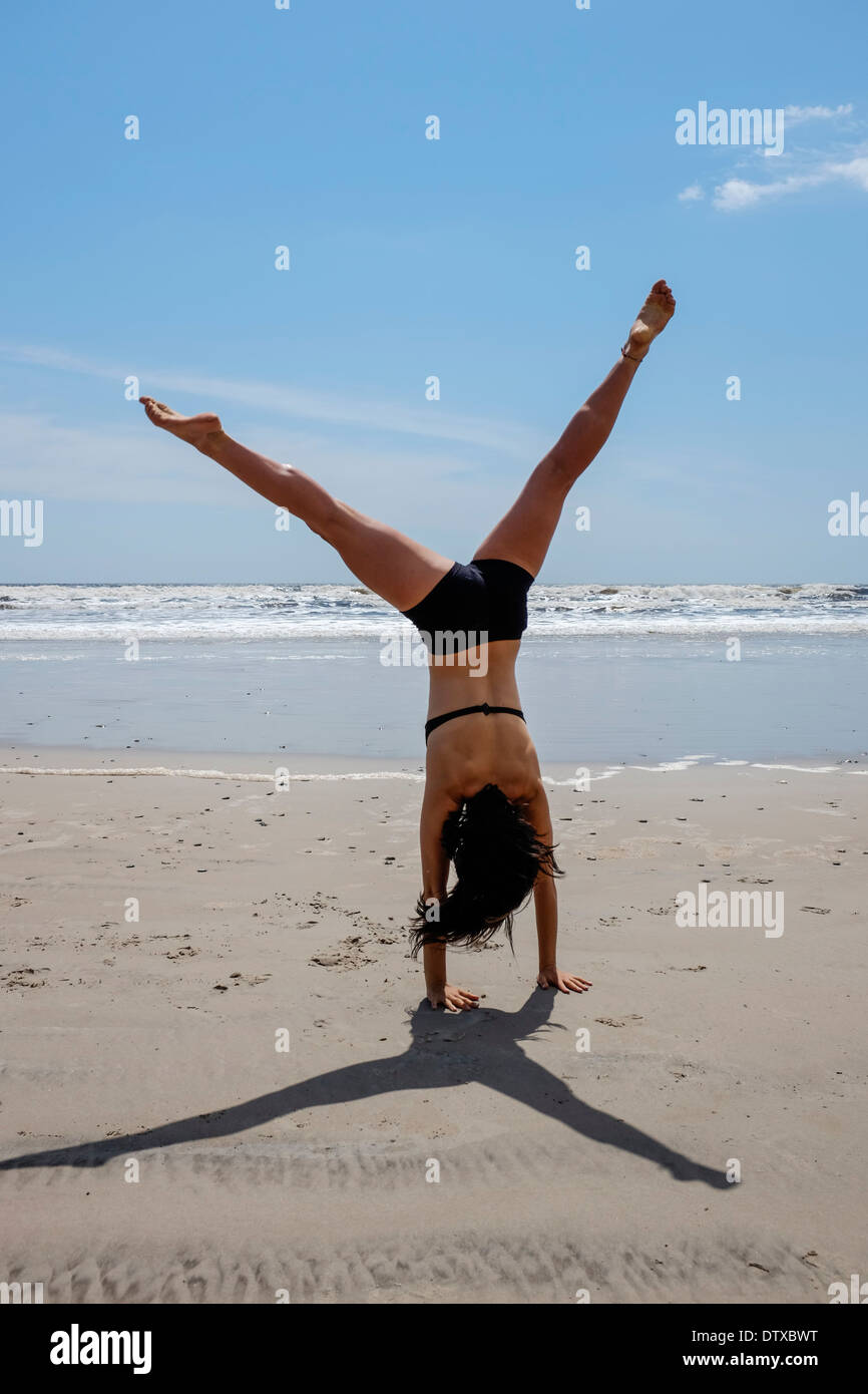 A healthy young teenager cartwheeling on a beach Stock Photo