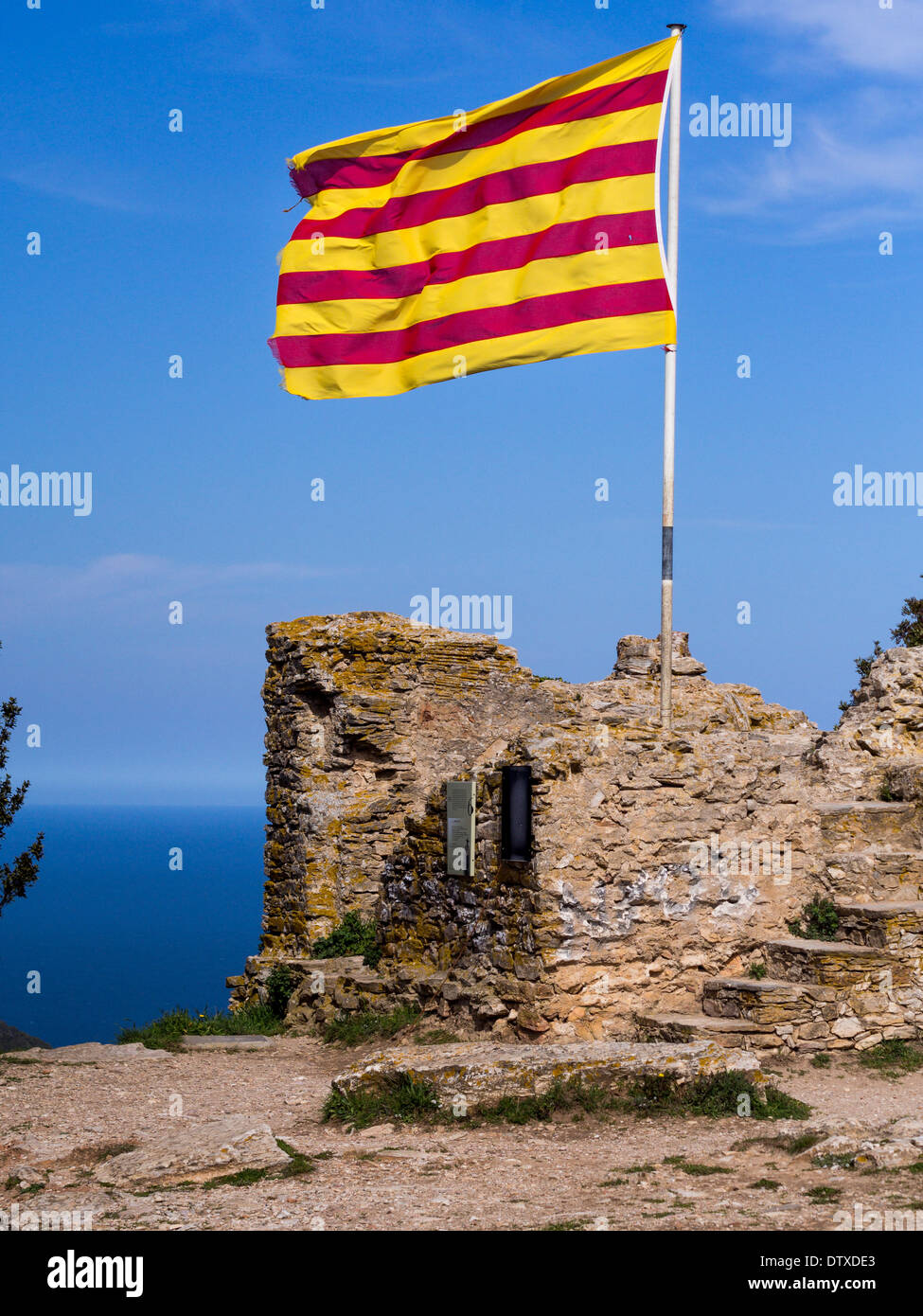 Catalonian Flag on the Fort above Begur. A bright yellow and red flag of Catalonia flies above the hilltop fort  overlooking sea Stock Photo