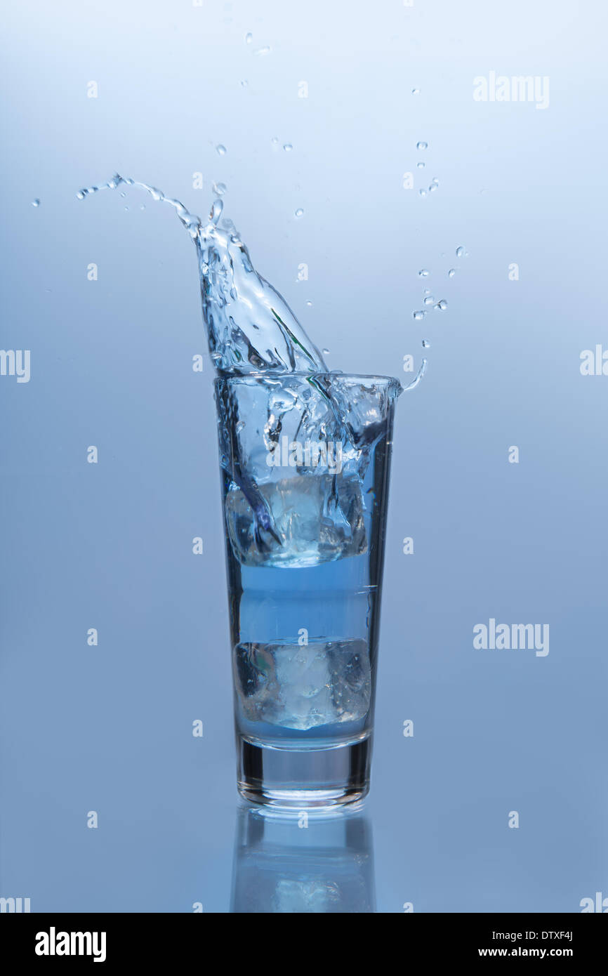 An ice cube falling into glass of water Stock Photo - Alamy