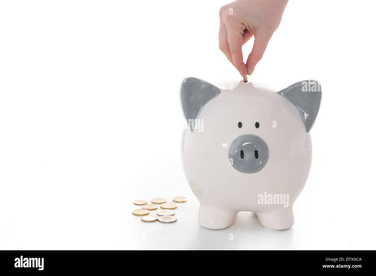 Hand putting coins into piggy bank Stock Photo - Alamy