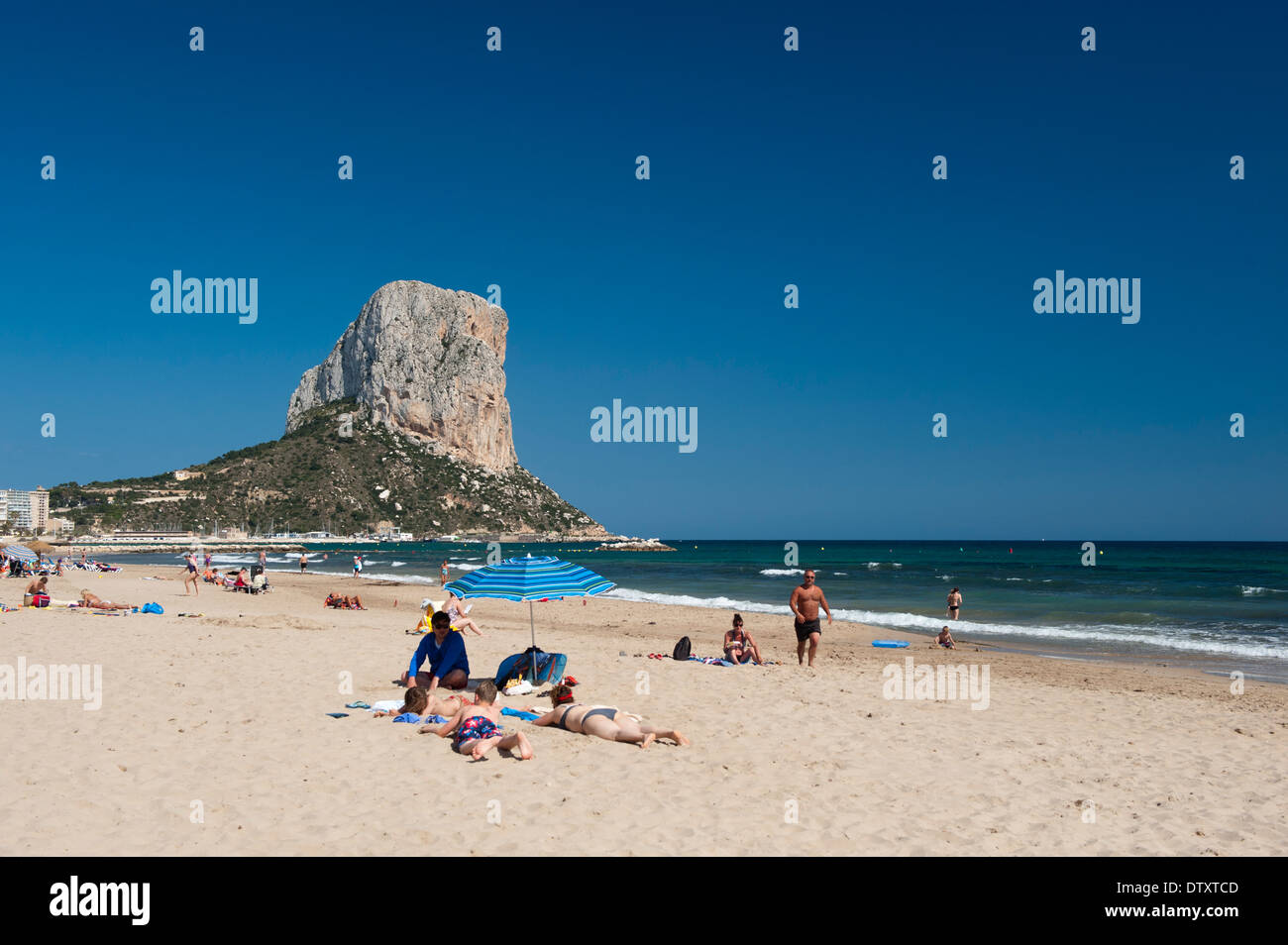 The imposing Penyal d'lfac outcrop in the bay of Calp, Costa Brava, Spain, with people on the beach in the foreground. Stock Photo