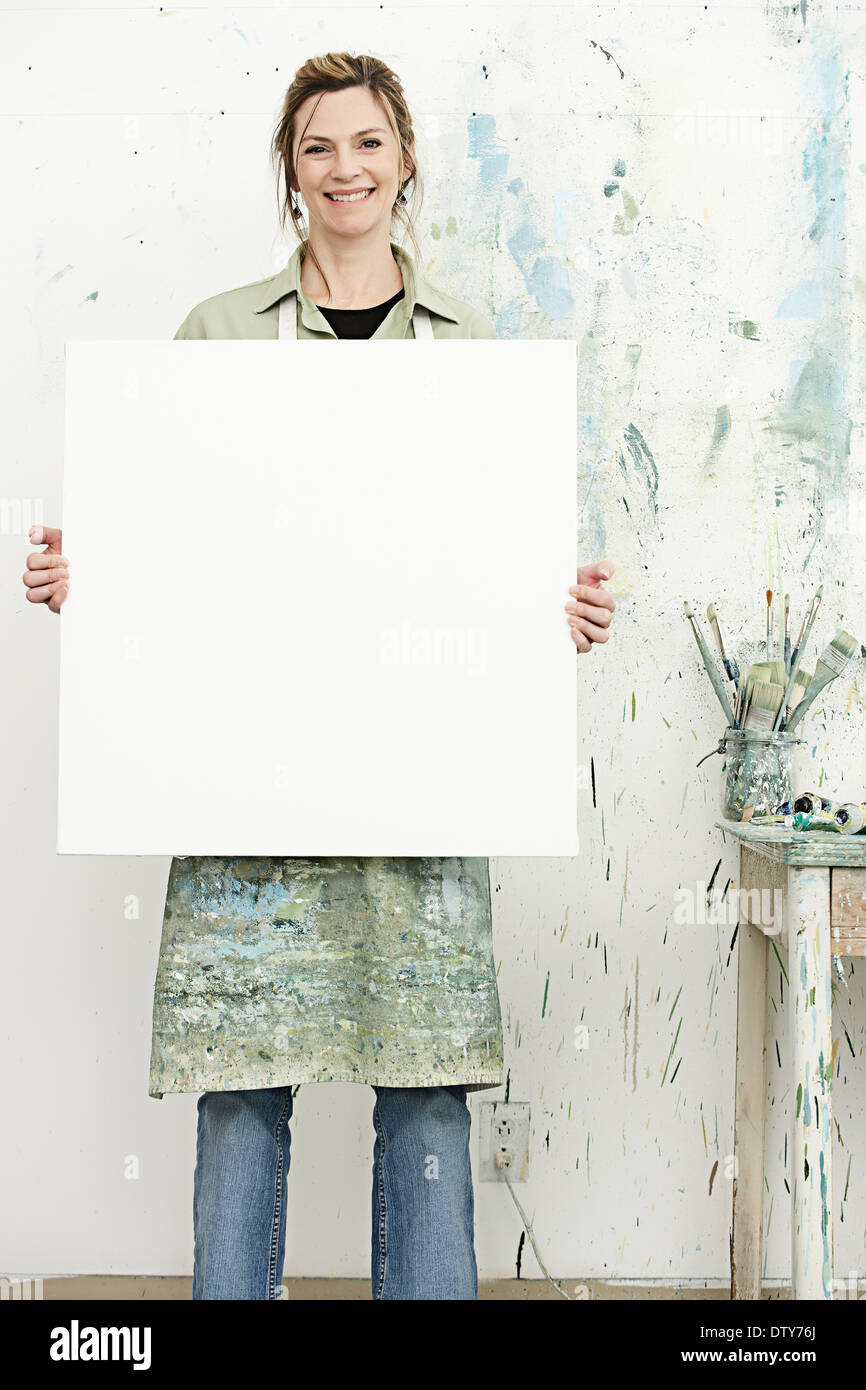Caucasian painter holding blank canvas in studio Stock Photo