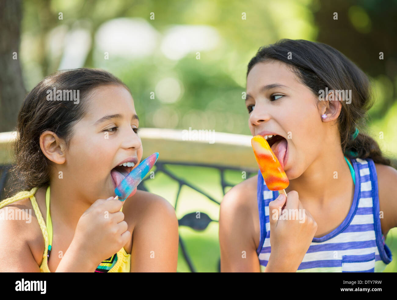 Mixed race girls eating flavored ice outdoors Stock Photo