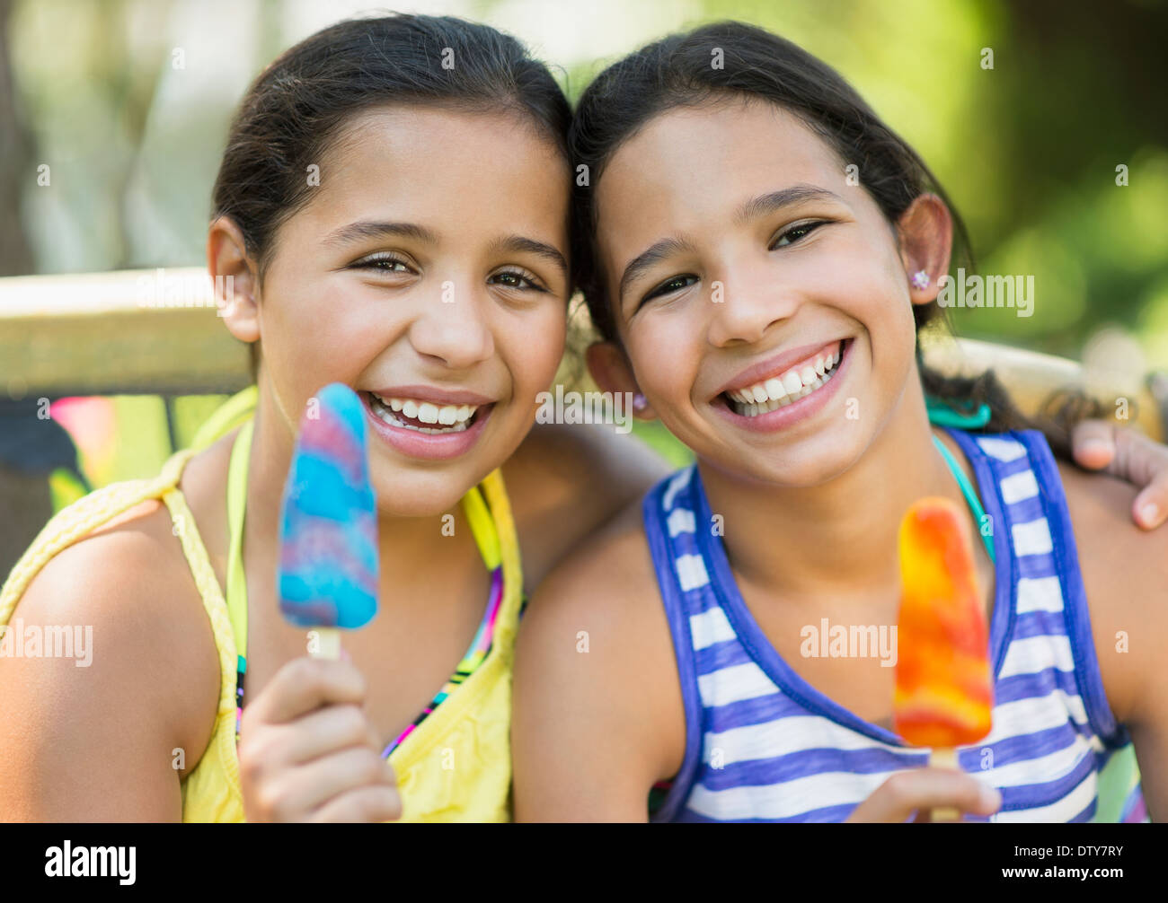 Mixed race girls eating flavored ice outdoors Stock Photo