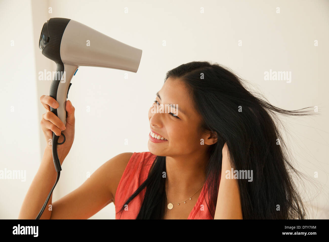 Chinese woman blow drying her hair Stock Photo