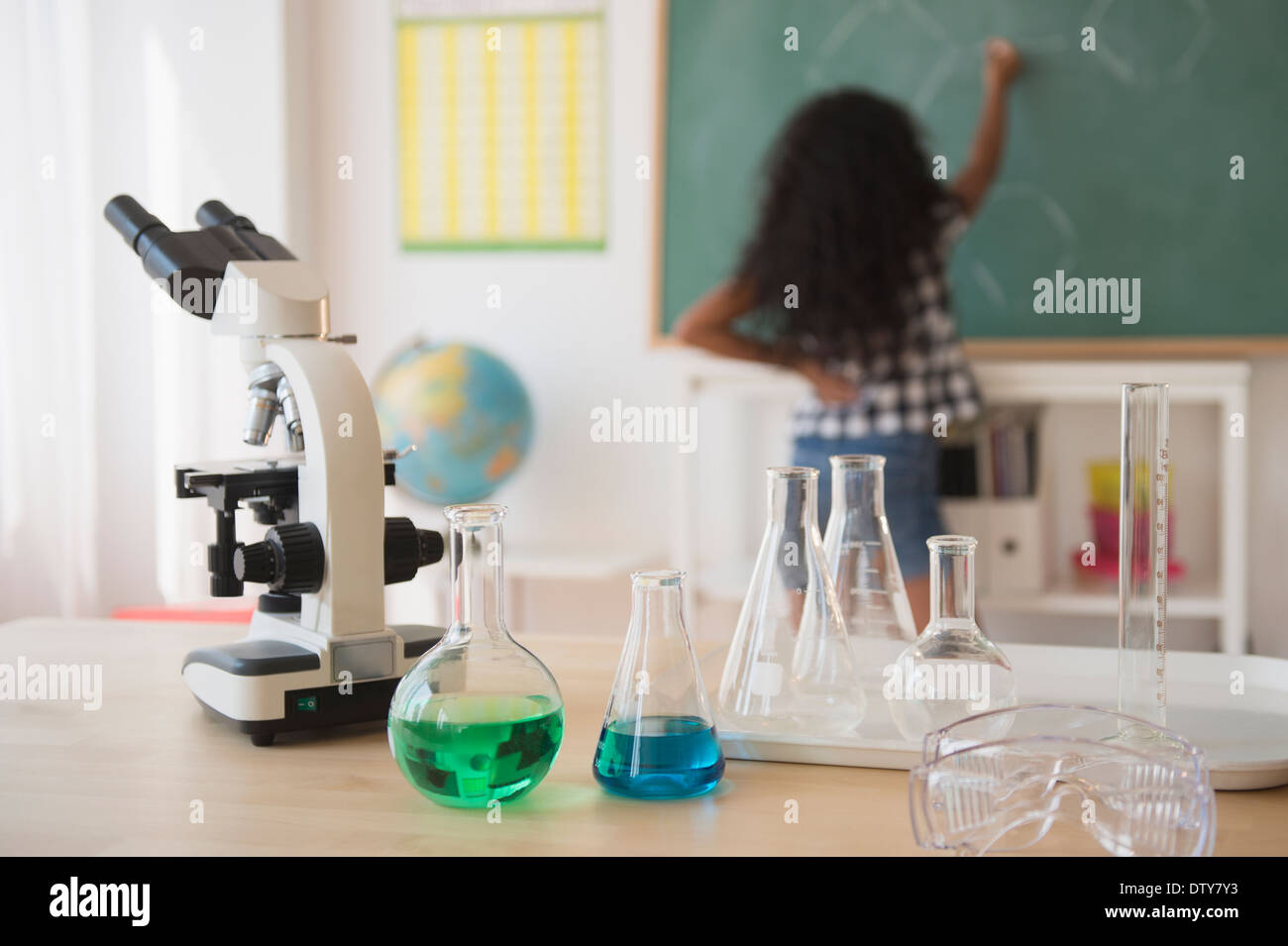 Mixed race student writing on chalkboard in classroom Stock Photo