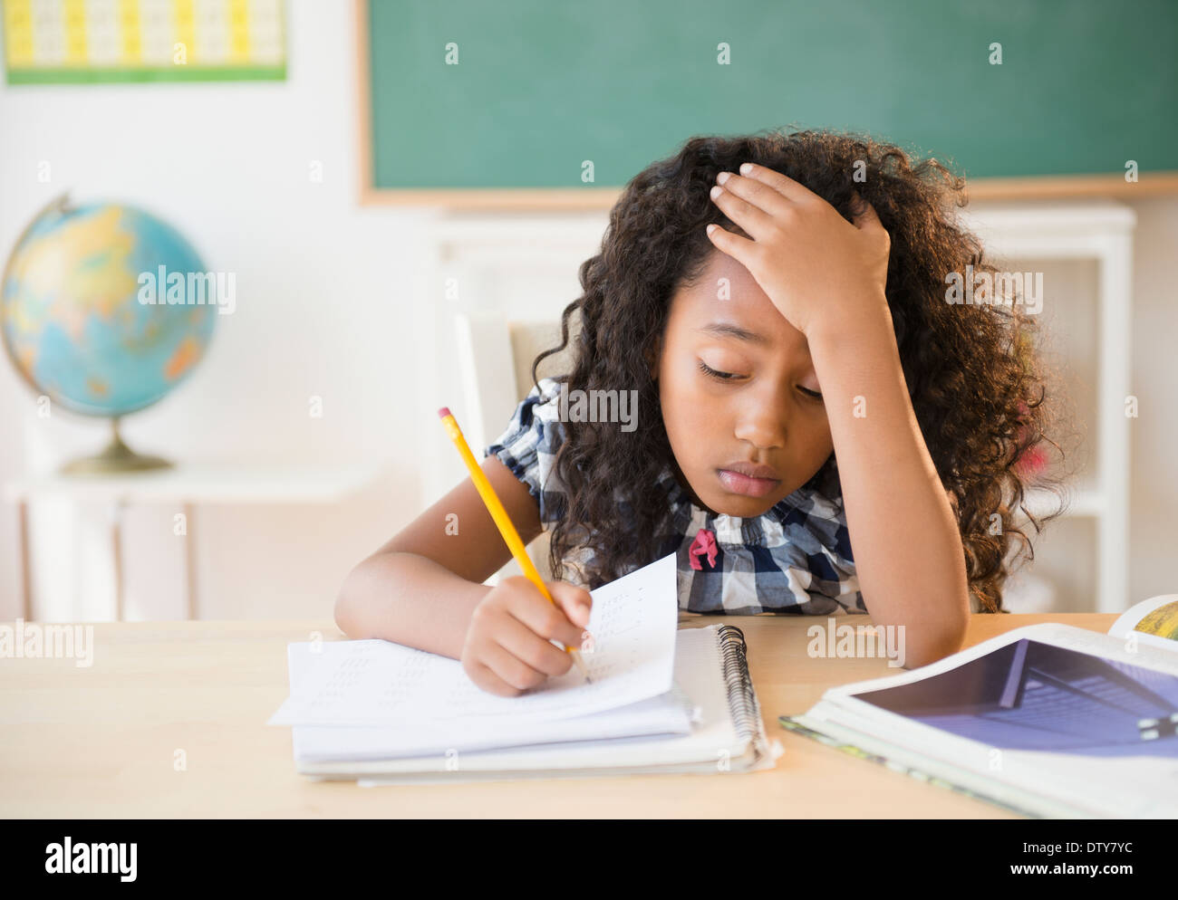 Frustrated mixed race student working in classroom Stock Photo