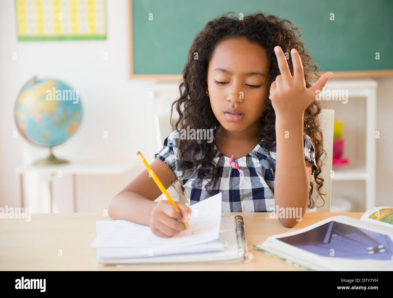 Mixed race student counting on fingers in classroom Stock Photo