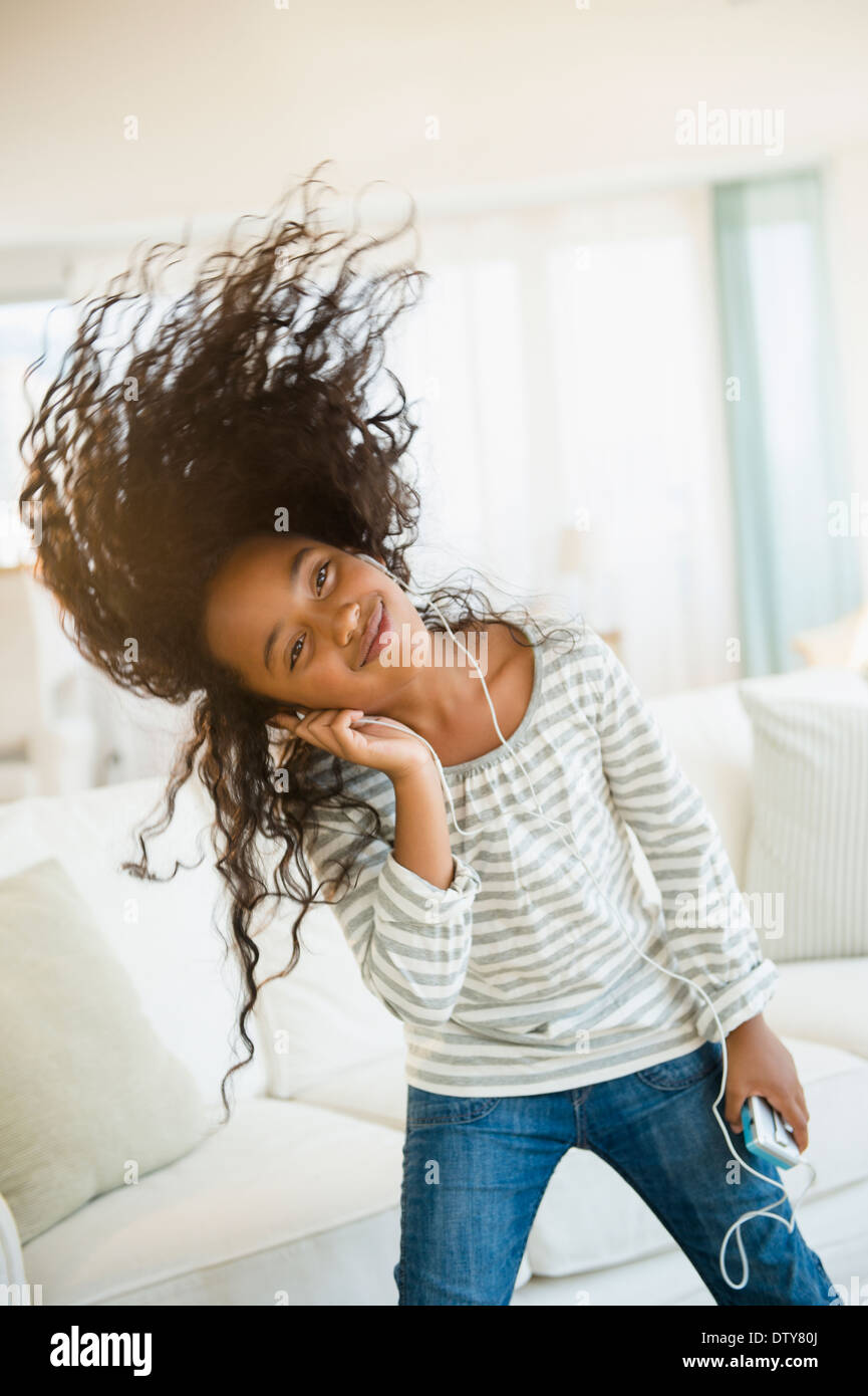 Mixed race girl dancing to headphones in living room Stock Photo