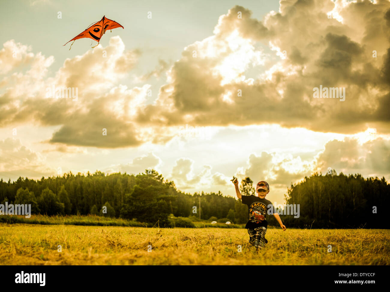 Caucasian boy flying kite in rural field Stock Photo