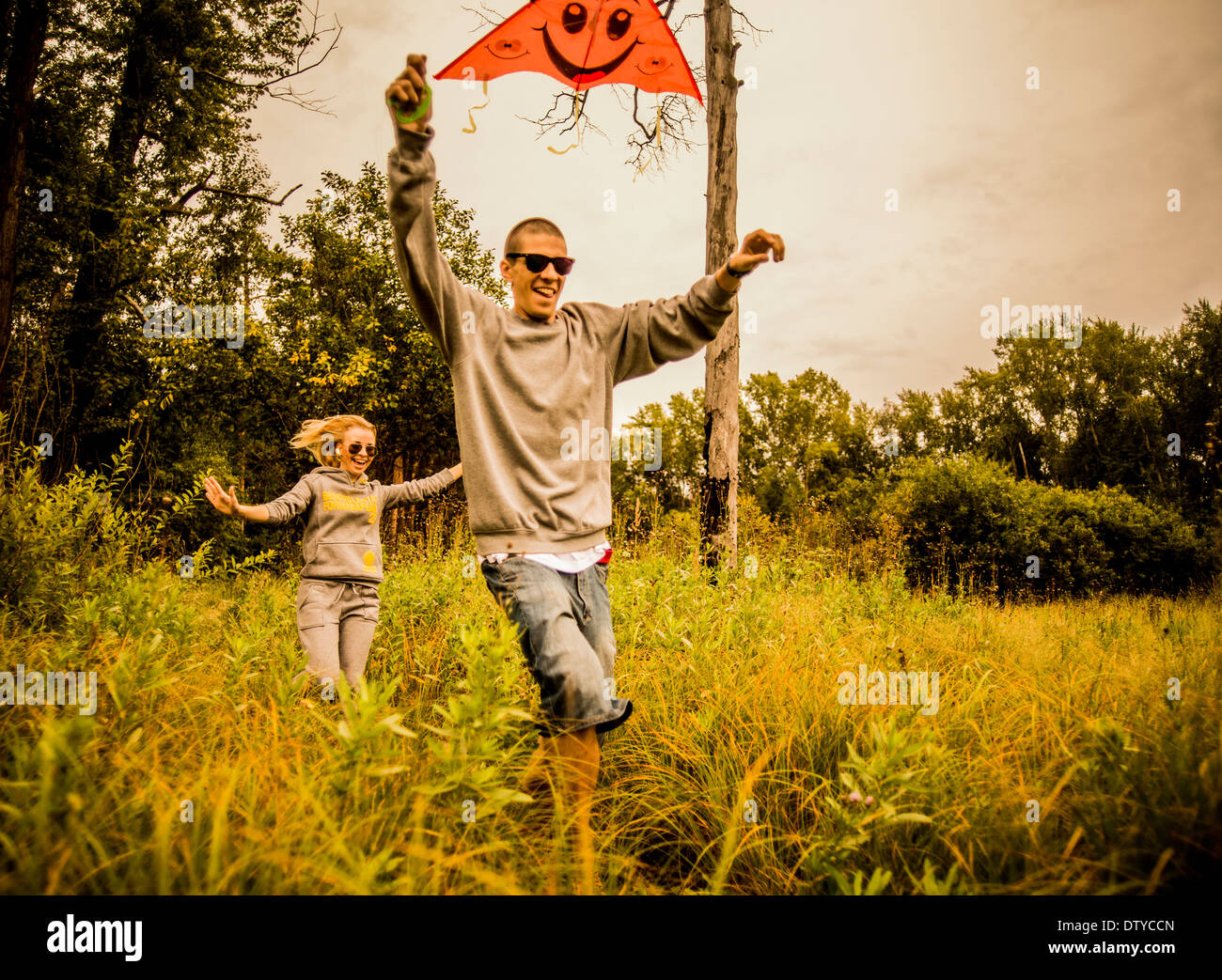 Caucasian couple flying kite in rural field Stock Photo