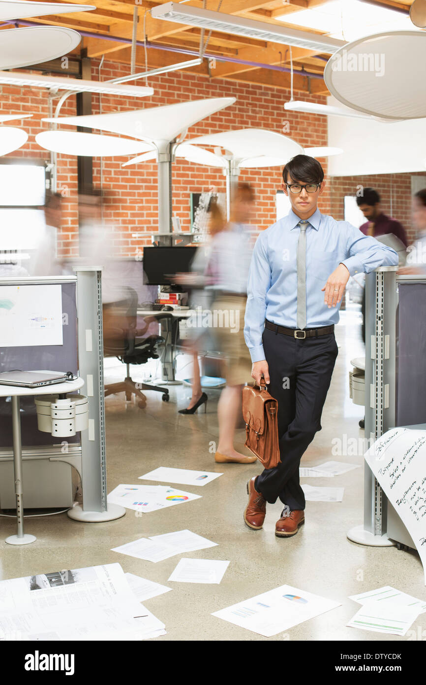 Businessman standing in busy office Stock Photo