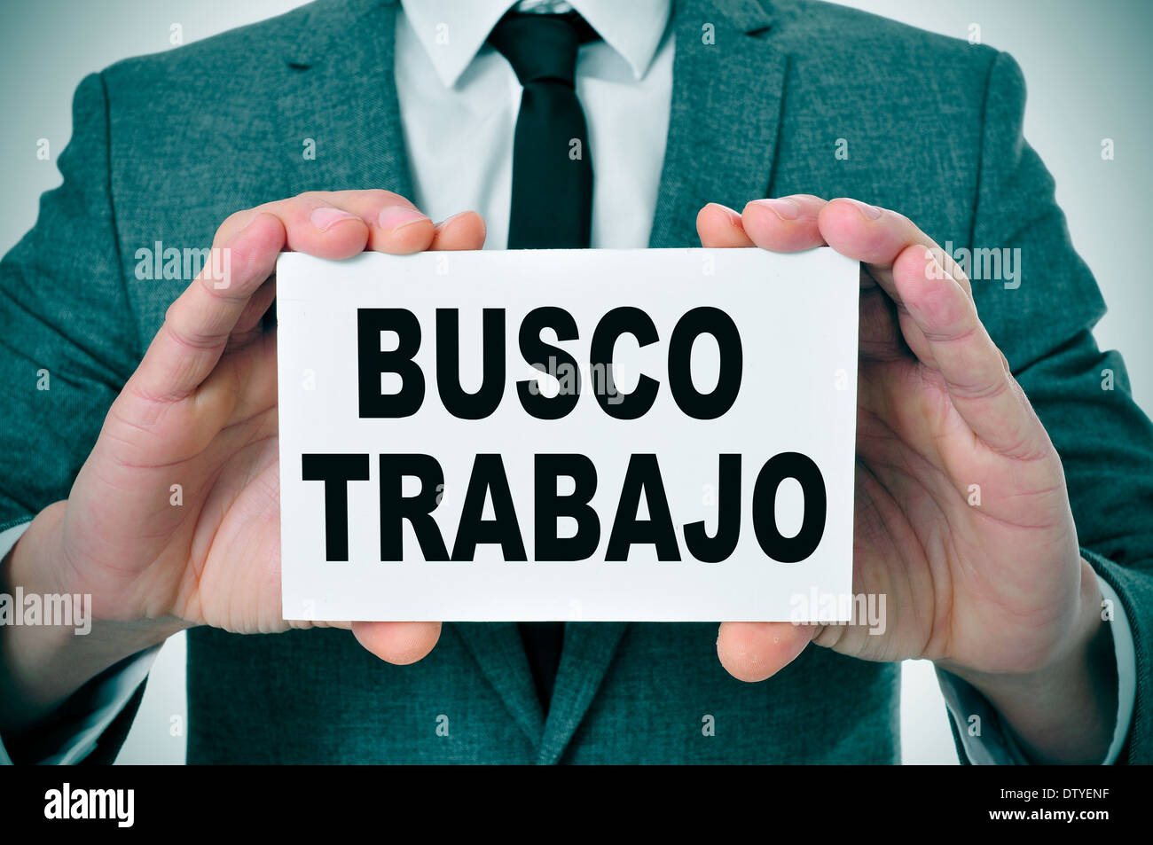 a man wearing a suit holding a signboard with text busco trabajo, looking for a job written in spanish Stock Photo - Alamy