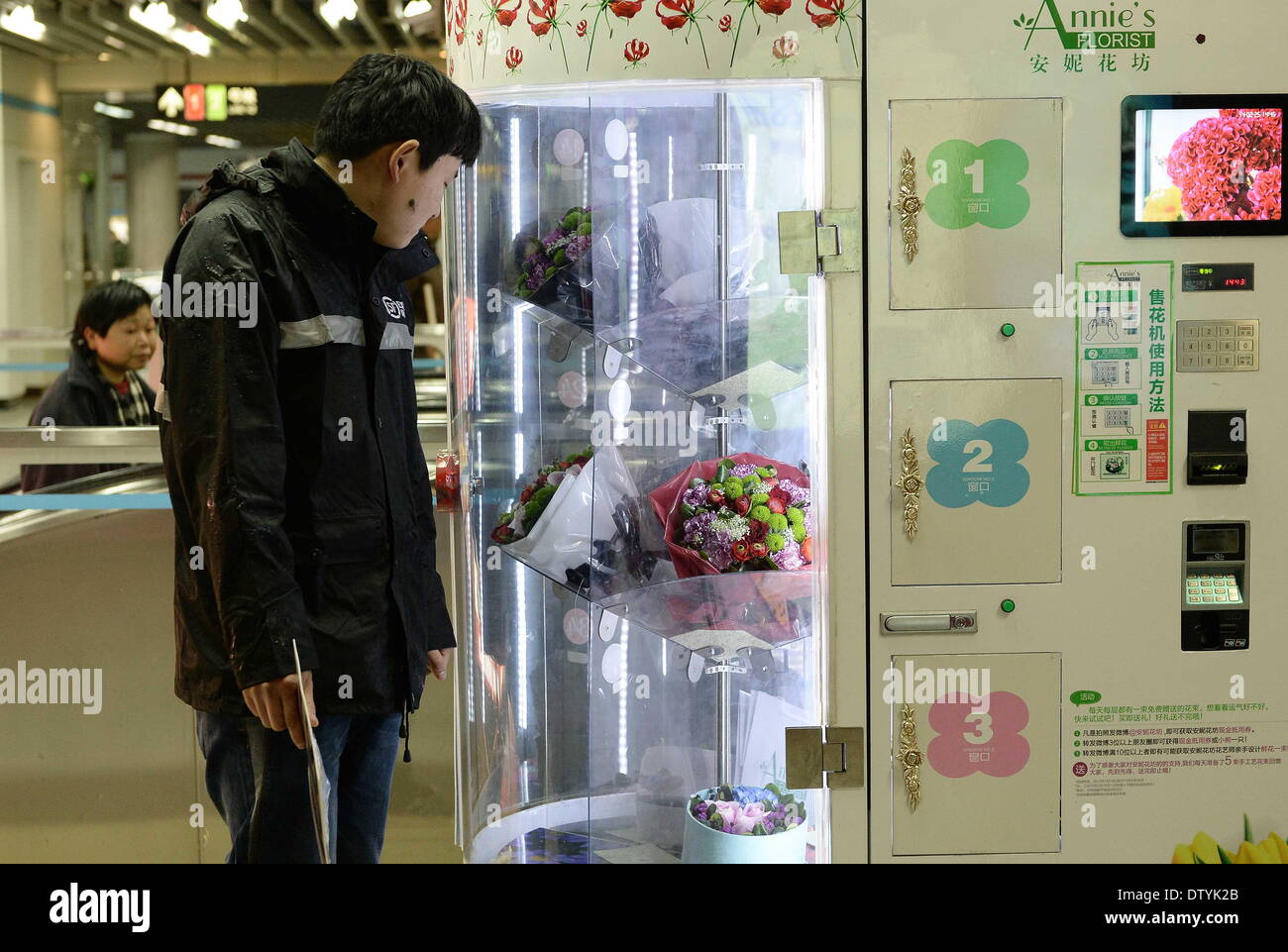 Shanghai. 25th Feb, 2014. A man looks at the bouquets of flowers inside a flower vending machine at a subway station in east China's Shanghai, Feb. 25, 2014. Through the vending machine, people can get flowers conveniently after inserting money for payment. © Lai Xinlin/Xinhua/Alamy Live News Stock Photo