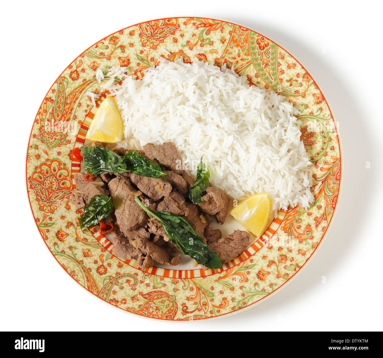 Chilli beef with crispy fried basil leaves, served with white basmati rice and lemon wedges, viewed from above Stock Photo