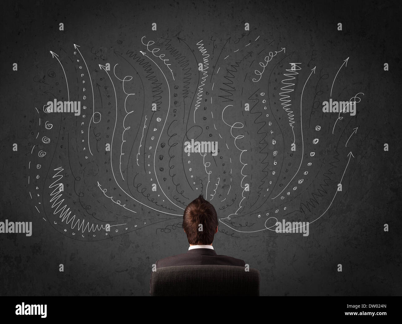 Businessman thinking with sketched arrows in front of a chalkboard Stock Photo