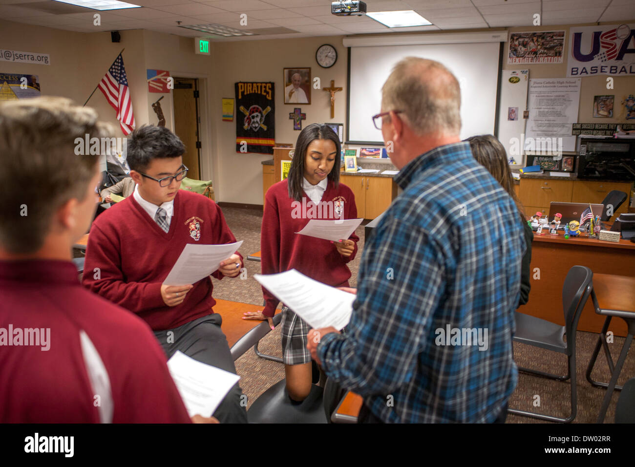 Uniformed Caucasian, Asian, and African American students interact with their teacher at a Catholic private high school. Stock Photo
