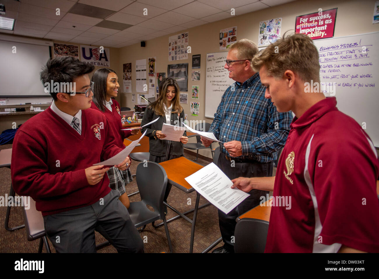 Uniformed Caucasian, Asian, and African American students interact with their teacher at a Catholic private high school. Stock Photo