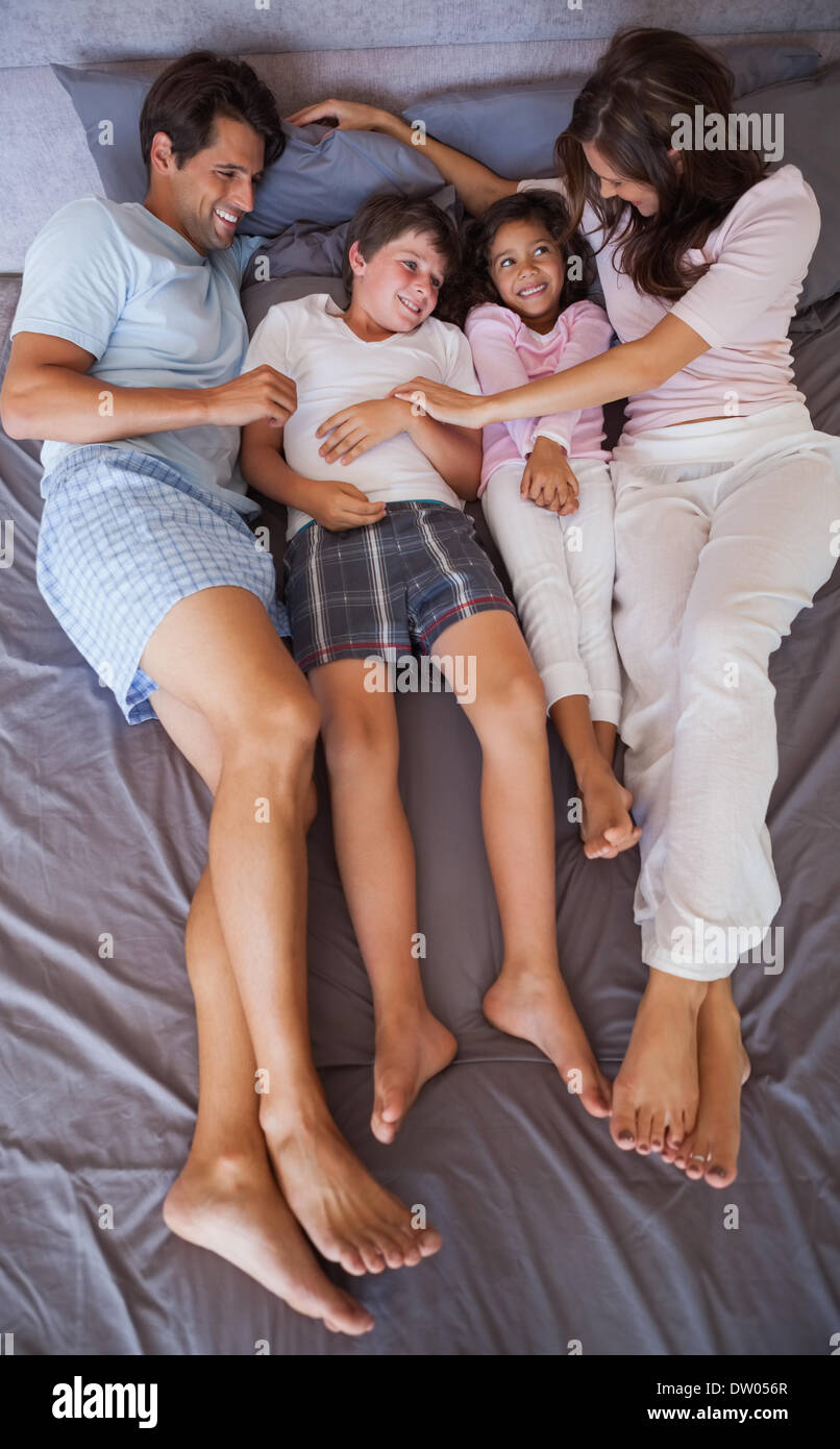 Smiling family lying together on bed Stock Photo