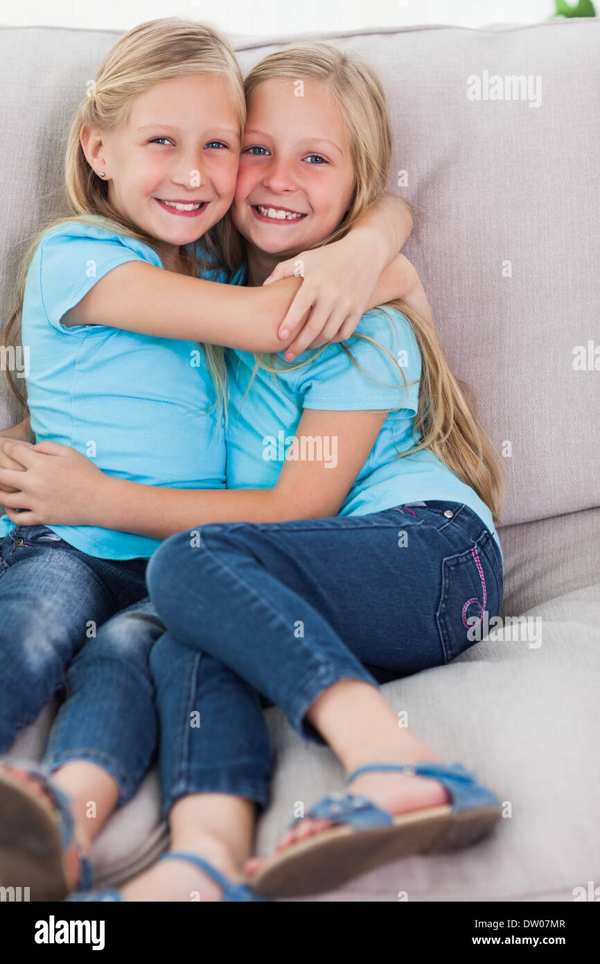 Young twins embracing each other on a couch Stock Photo Alamy