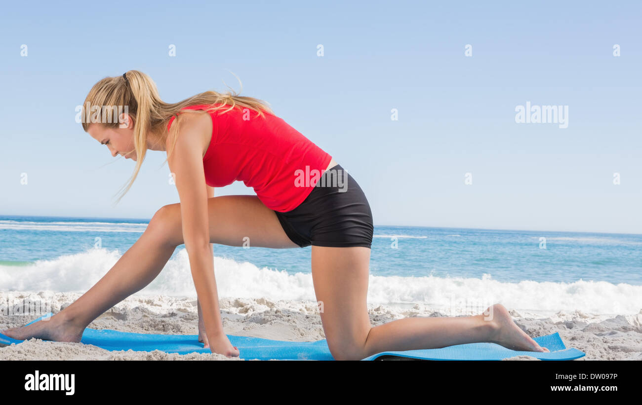 Fit blonde stretching leg on exercise mat Stock Photo - Alamy