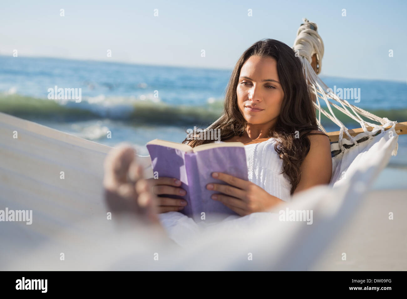 Content woman lying on hammock reading book Stock Photo - Alamy
