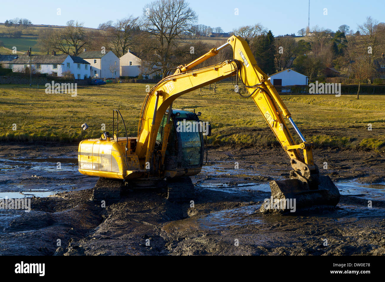 Dredging using a JCB JS130 tracked excavator clearing a choked water body. Stock Photo