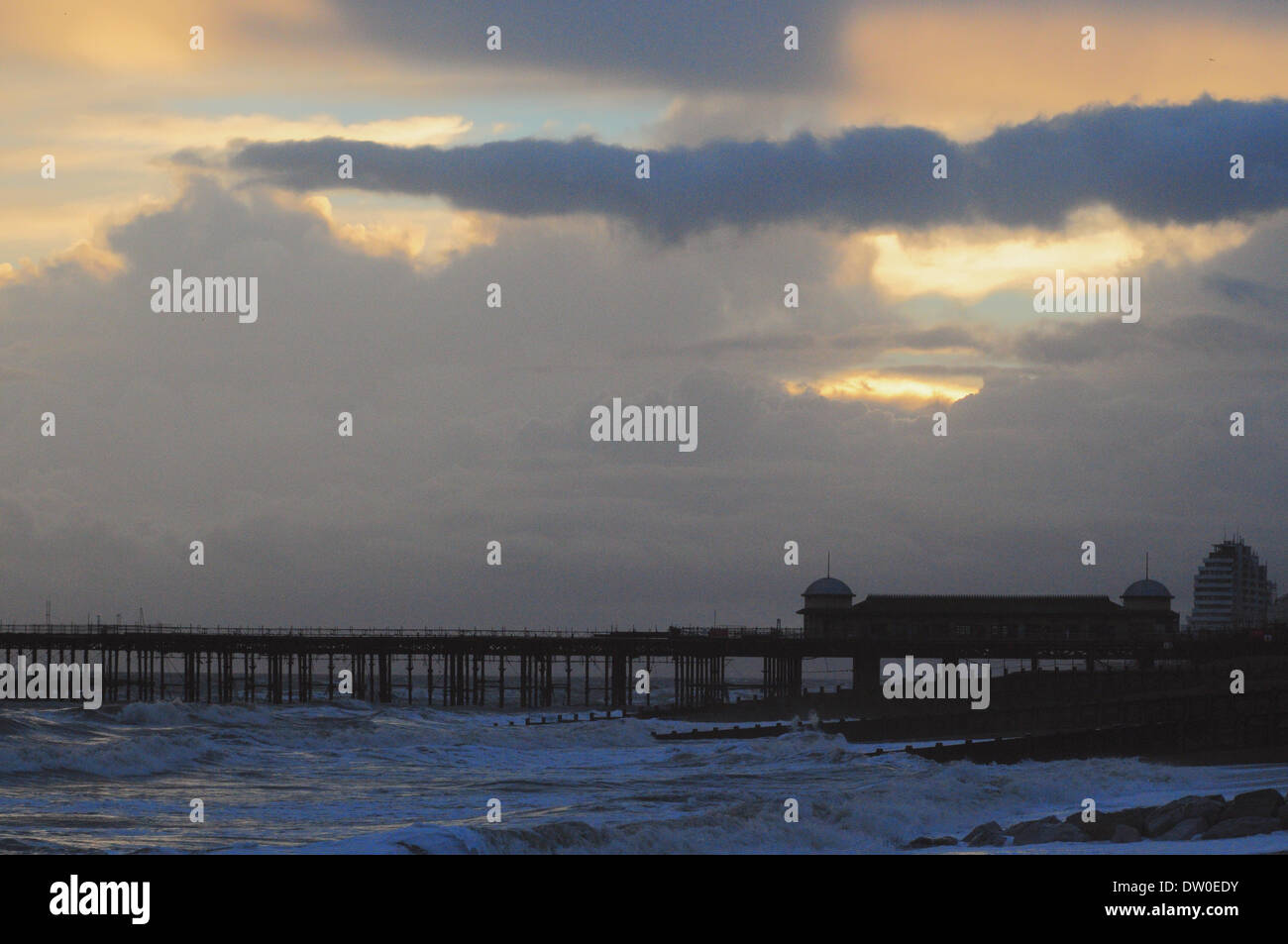 Hastings, East Sussex, UK. 25th Feb, 2014. Sunset shines through stormy clouds above the pier at Hastings, East Sussex, after a day of frequent heavy showers. David Burr/Alamy Live News Stock Photo