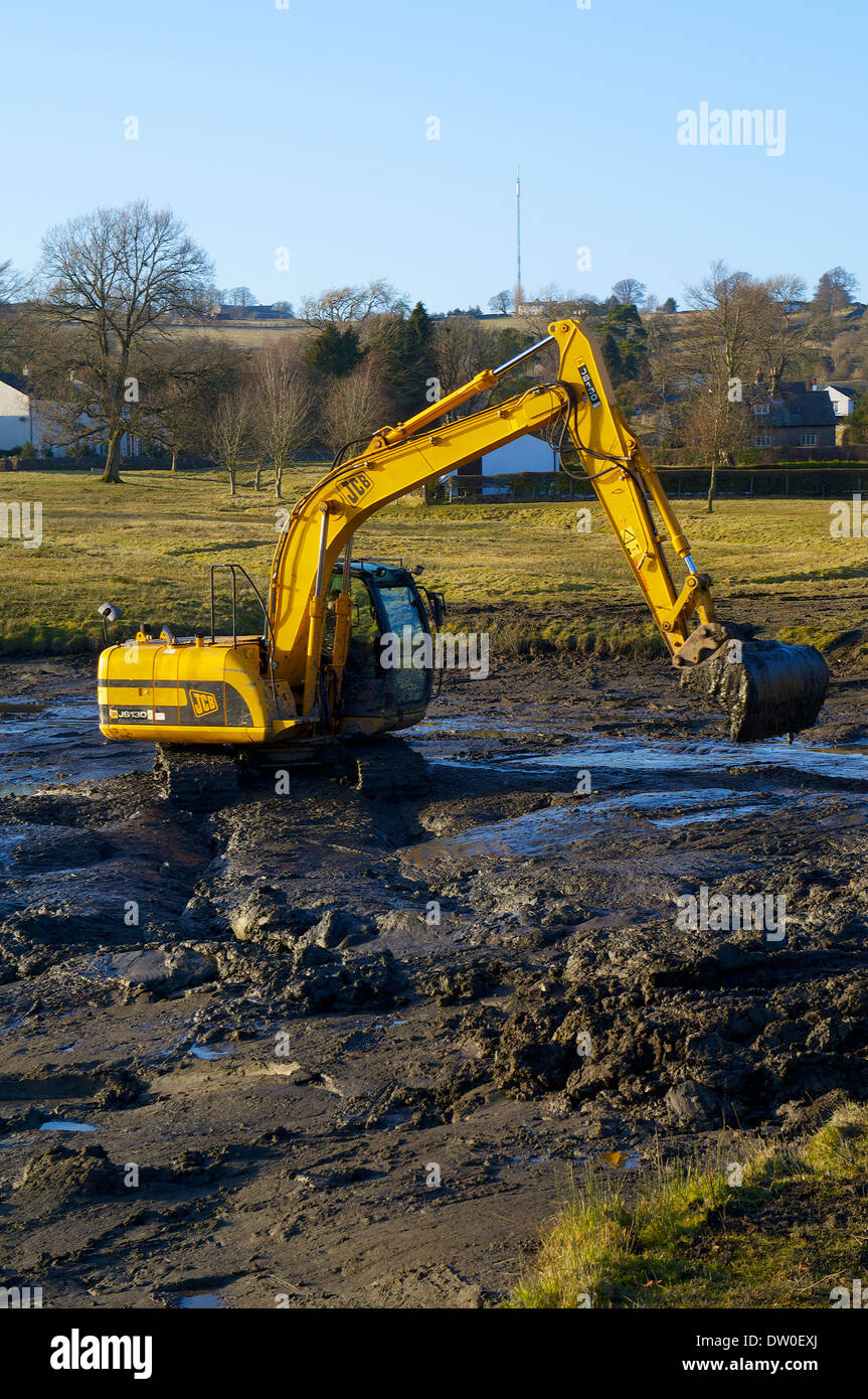 Dredging using a JCB JS130 tracked excavator clearing a choked water body. Stock Photo