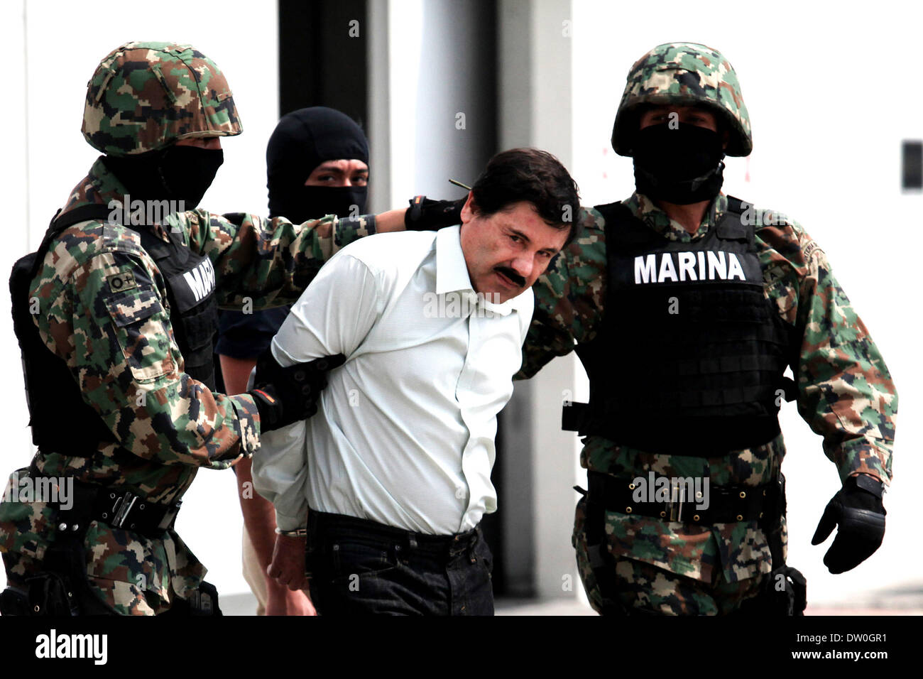 Mexico City, Mexico. 22nd Feb, 2014. Mexican Navy soldiers escort Joaquin Guzman Loera (front), alias ''El Chapo Guzman'', leader of the Sinaloa Cartel, during his show up in front of the press, at the Mexican Navy hangar in Mexico City, capital of Mexico, on Feb. 22, 2014. Mexican President Enrique Pena Nieto on Saturday confirmed the capture of the world's most wanted drug lord, Joaquin Guzman Loera, known as El Chapo, in the Pacific resort of Mazatlan. © Jair Cabrera Torres/NurPhoto/ZUMAPRESS.com/Alamy Live News Stock Photo