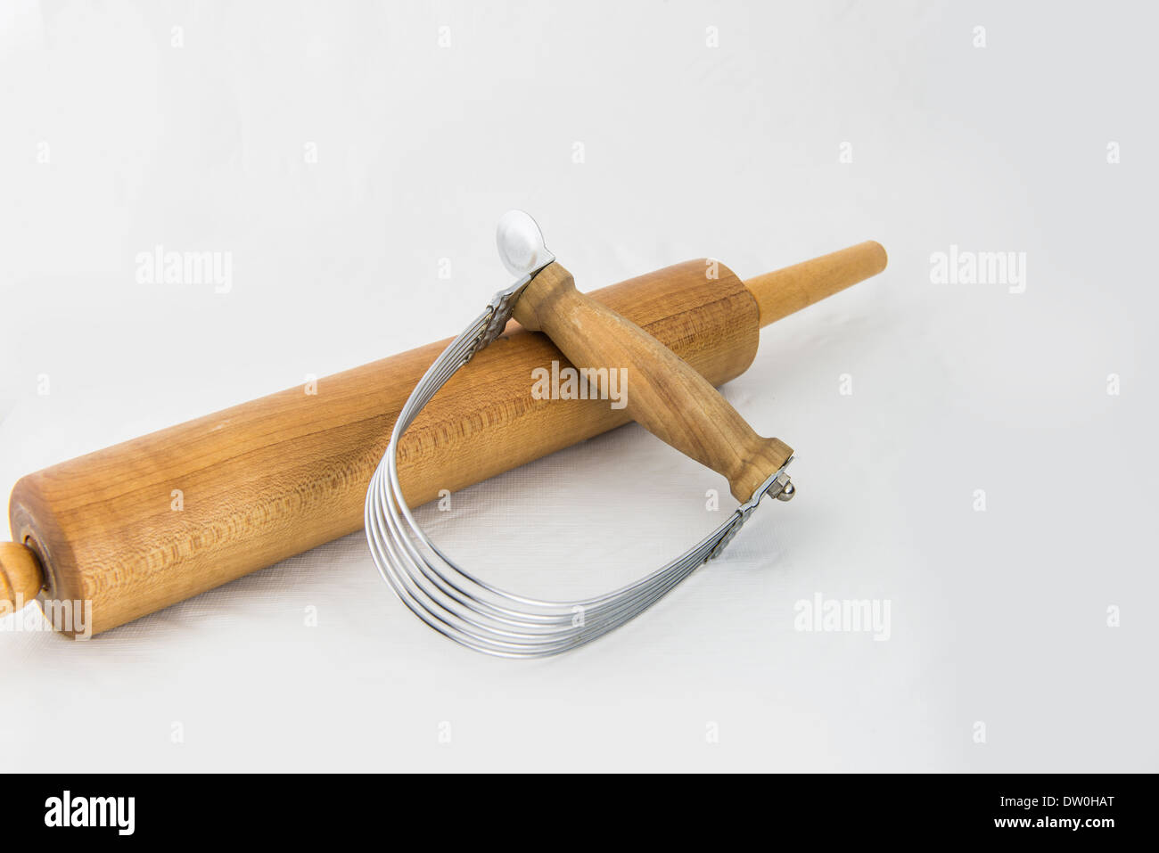 Two kitchen appliances used in the making of pie cruist. A pastry blender, and a rolling pin, isolated on white. Stock Photo