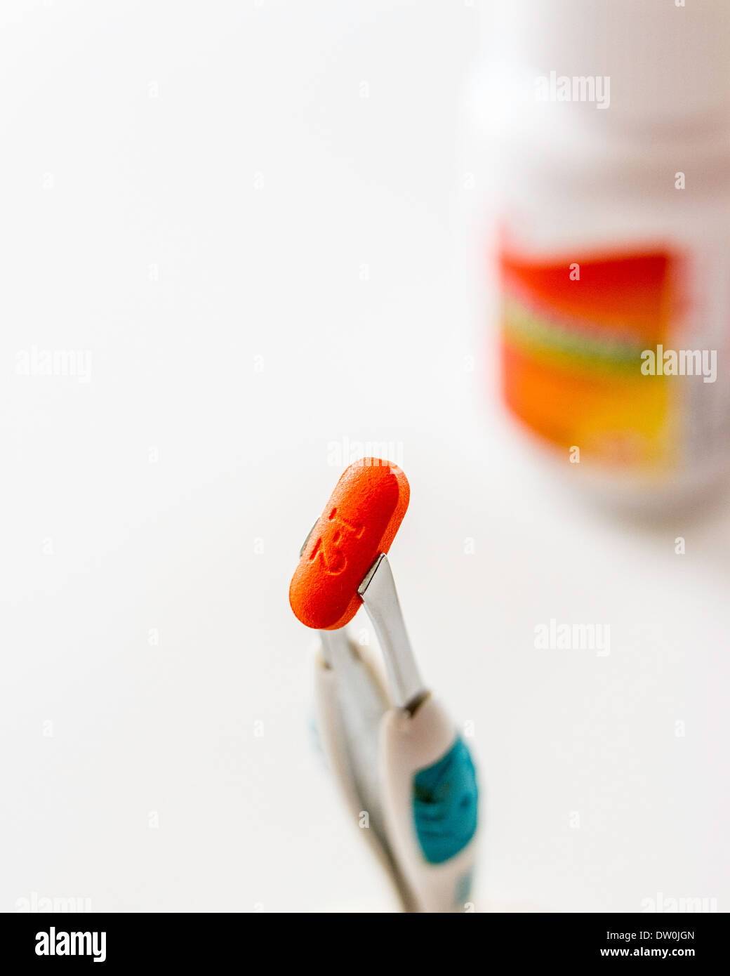 A generic brand Ibuprofen tablet with bottle held by tweezers Stock