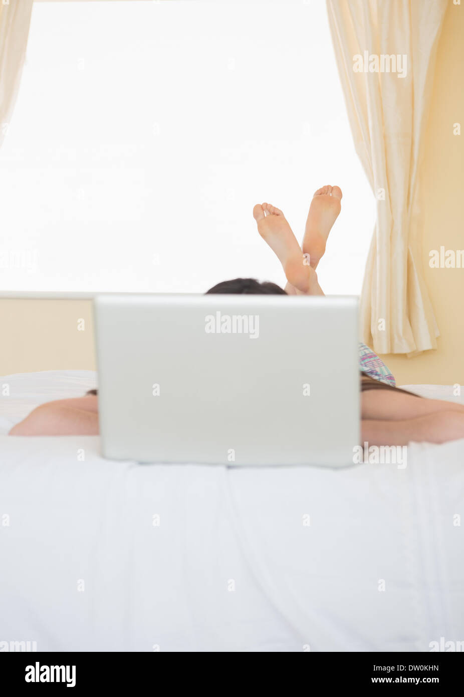 Girl lying on a bed behind a laptop Stock Photo - Alamy