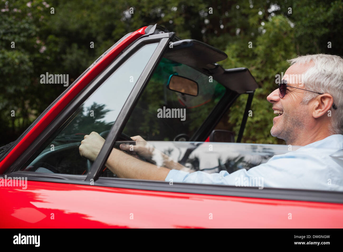 Smiling handsome man driving red convertible Stock Photo
