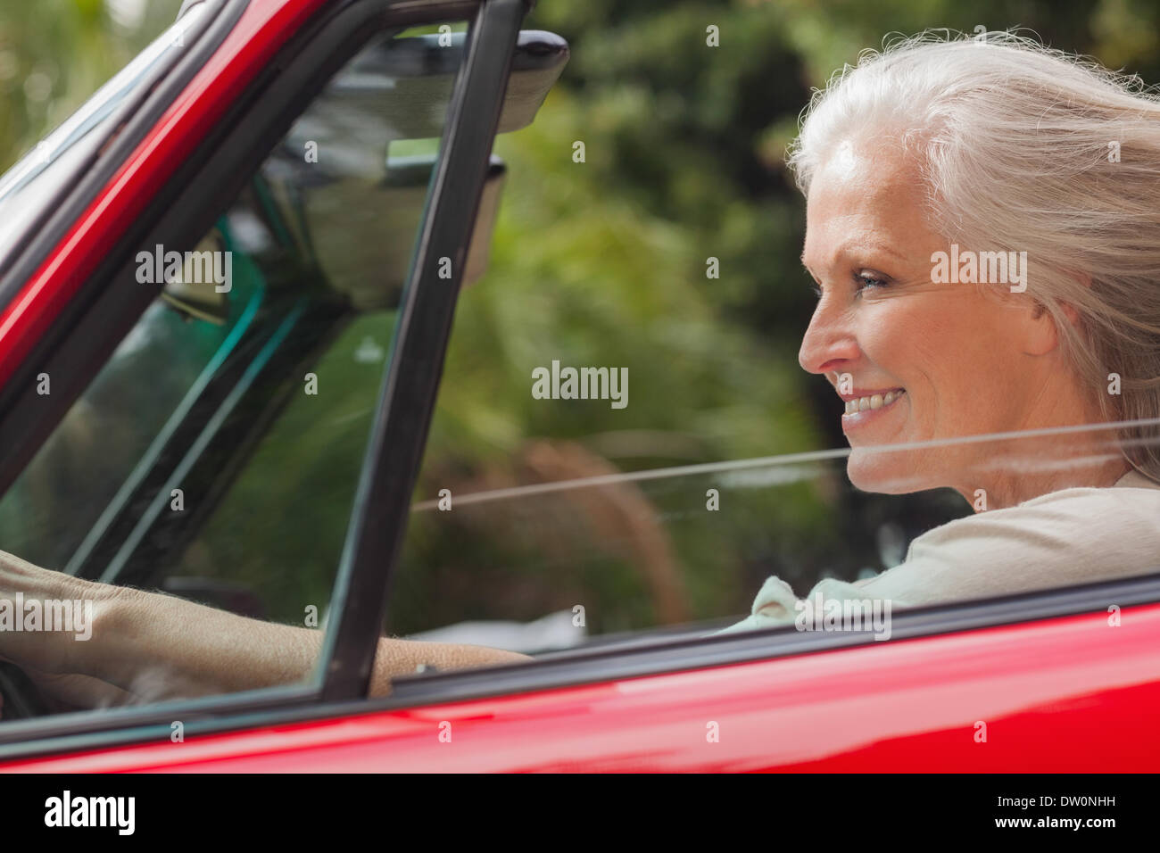 Smiling mature woman driving red convertible Stock Photo