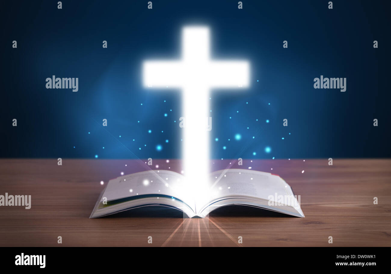 Open holy bible with glowing cross in the middle Stock Photo