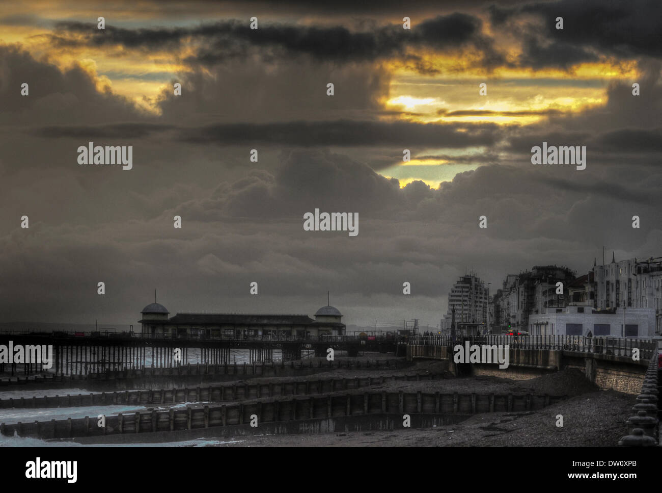 Hastings, East Sussex, UK..25 Feb 2014..Setting sun shines through storm clouds over Hastings Pier and town after a day of heavy showers and sunny intervals. HDR image. David Burr/Alamy Live News. Stock Photo
