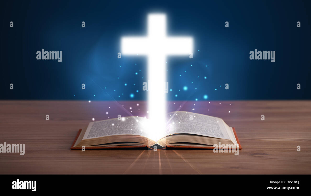 Open holy bible with glowing cross in the middle Stock Photo