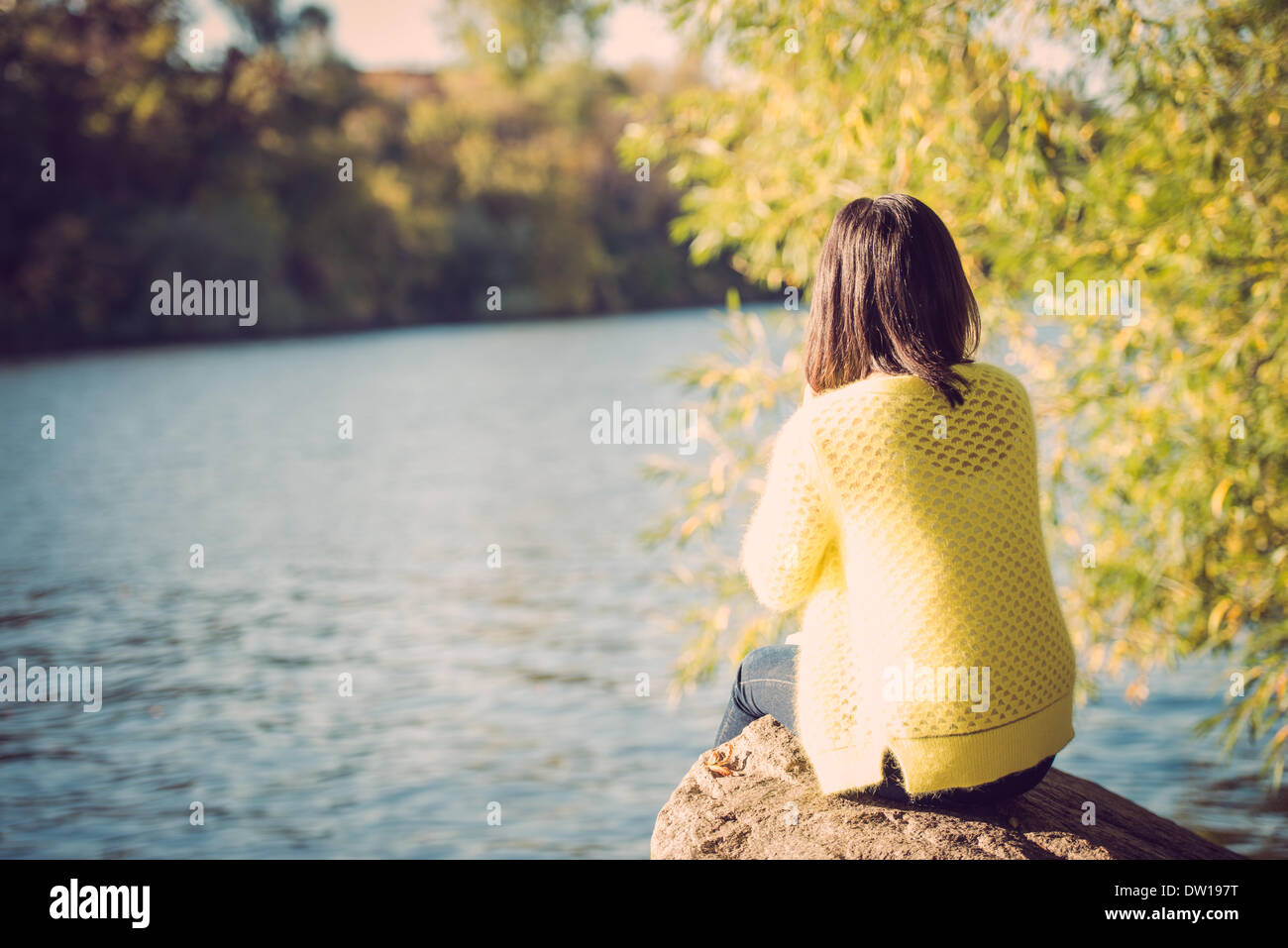 Woman sitting next to a river Stock Photo - Alamy