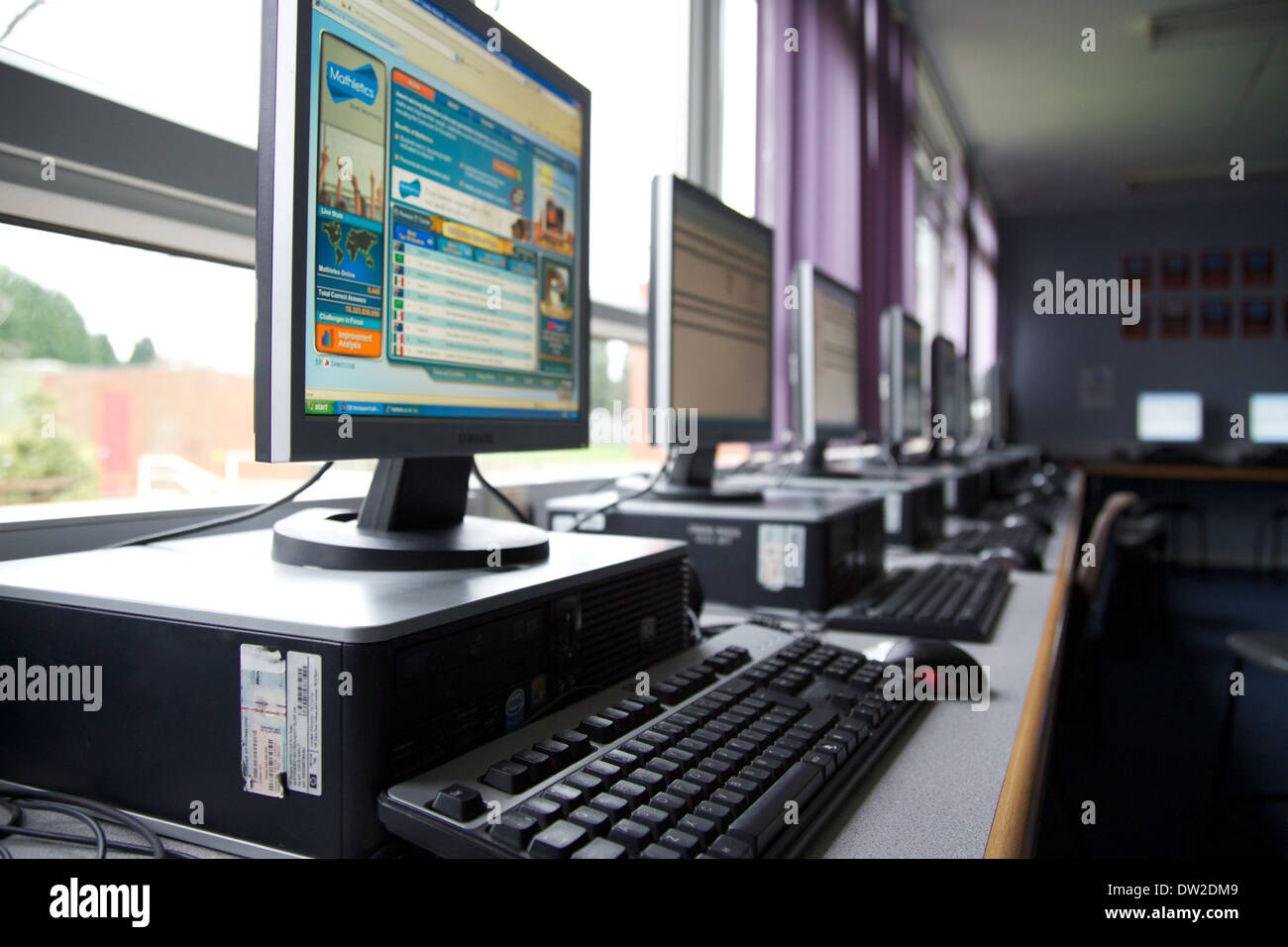 A line of desktop PCs computers in a UK classroom used for ICT lessons Stock Photo