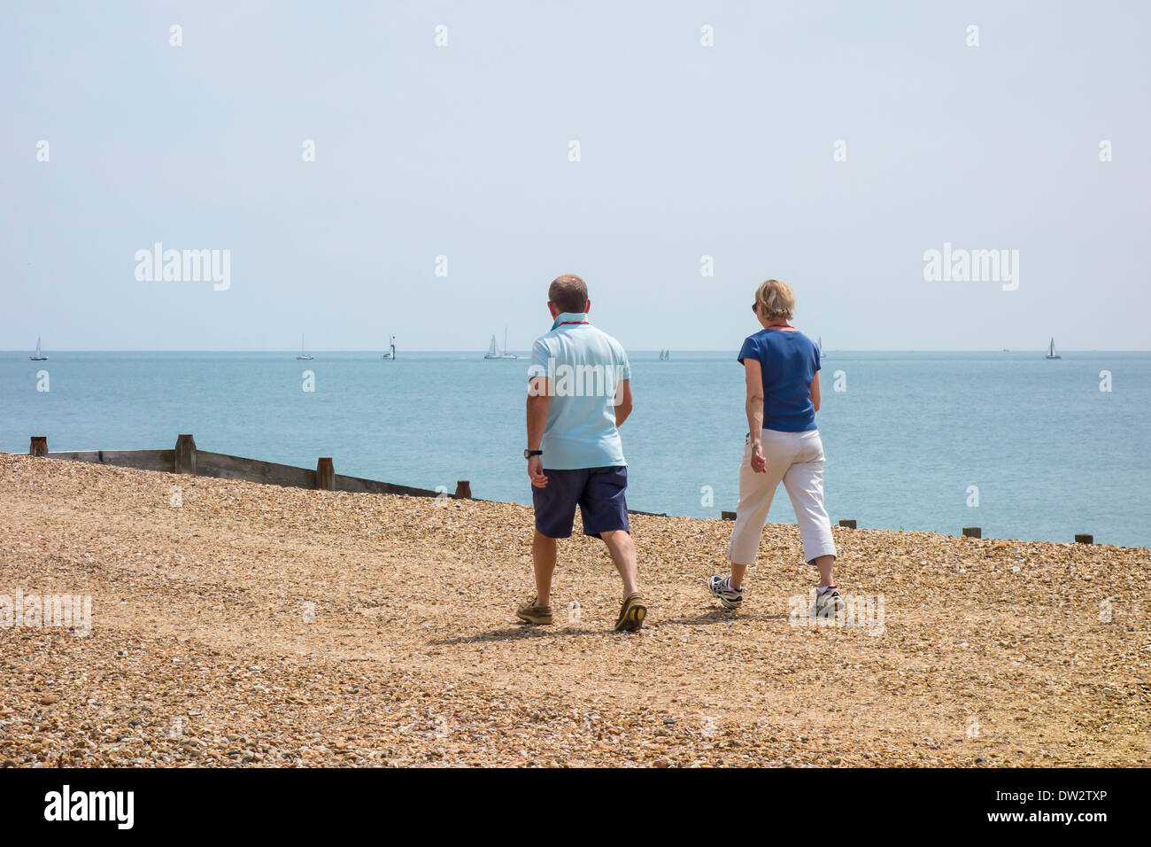 Middle age couple walking on a beach on Hayling Island, Hampshire Stock Photo