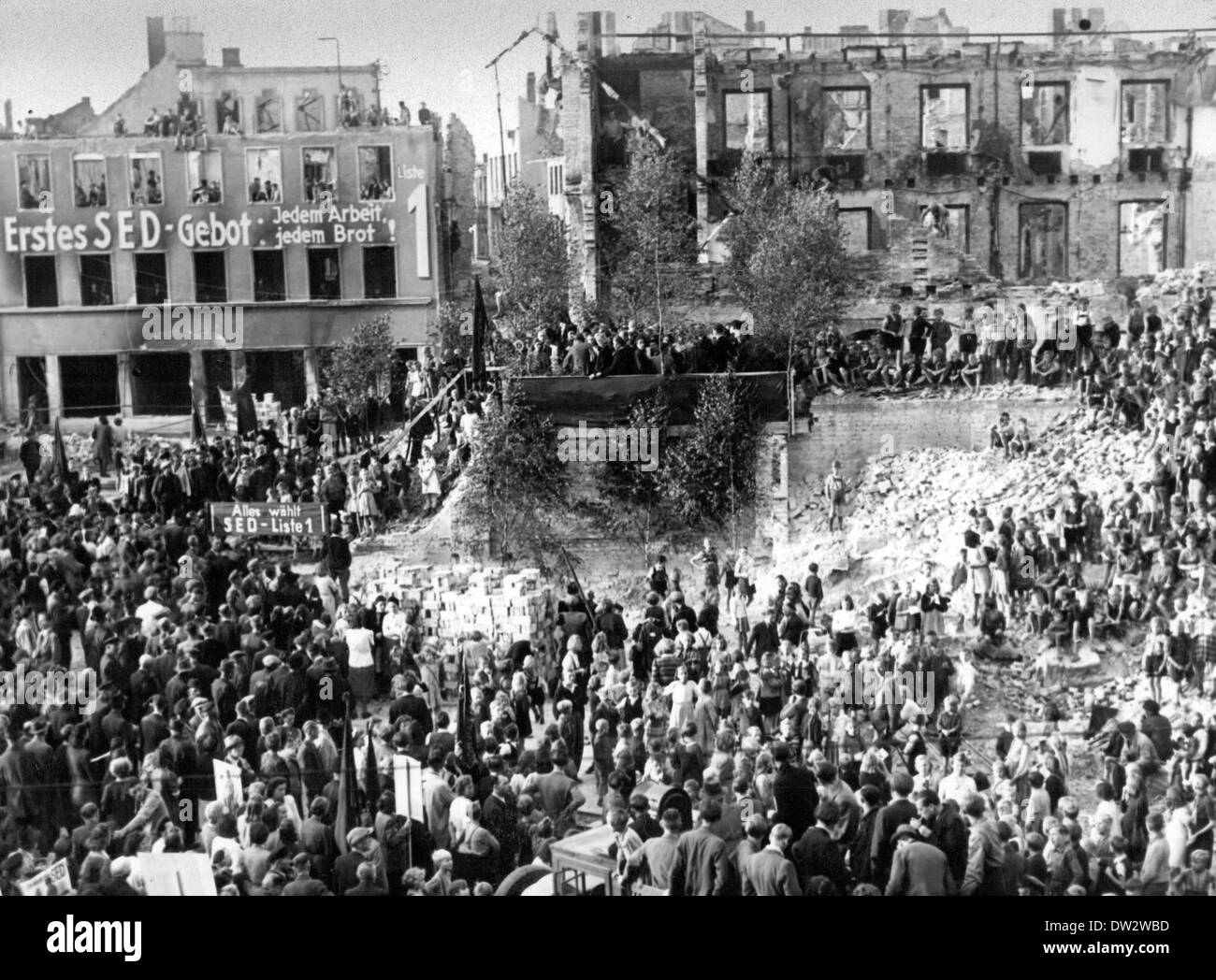 People gather for a rally during the first municipal election in the devastated center of Frankfurt (Oder), Germany, 1946. The lettering on the building facade and a poster reads 'First SED precept: Work and bread for everyone' and 'Everyone elects the SED - List 1'. Photo: Kotterba Collection - NO WIRE SERVICE (Inferior quality due to historical template) Stock Photo