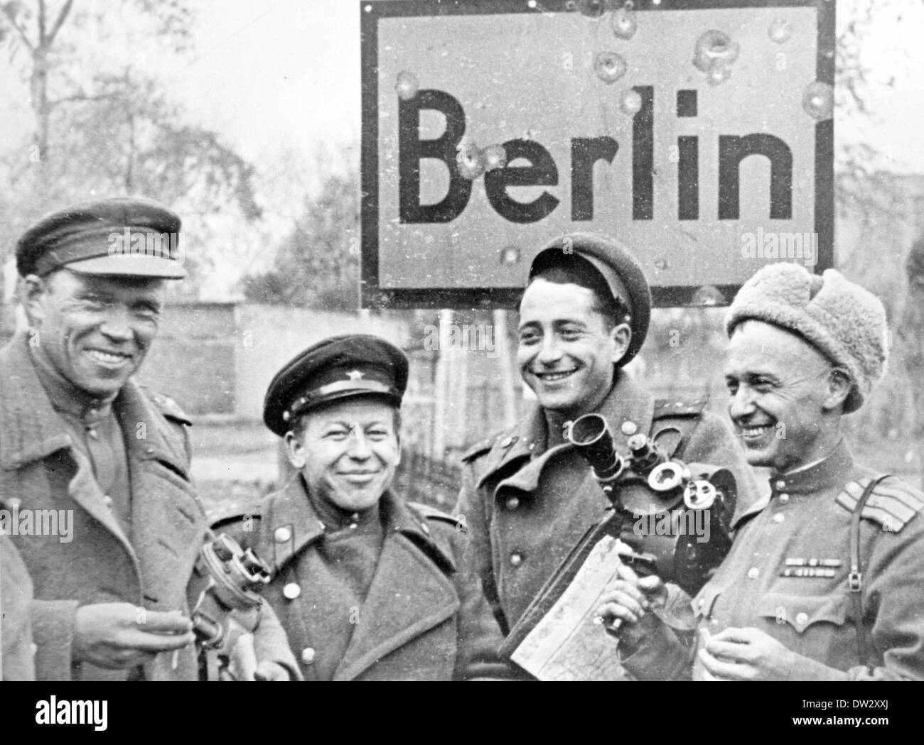 End of the war in Berlin 1945 - Soviet soldiers holding camera equipment and a map are photographed in front of a city sign in Berlin, Germany. Fotoarchiv für Zeitgeschichte - NO WIRE SERVICE Stock Photo