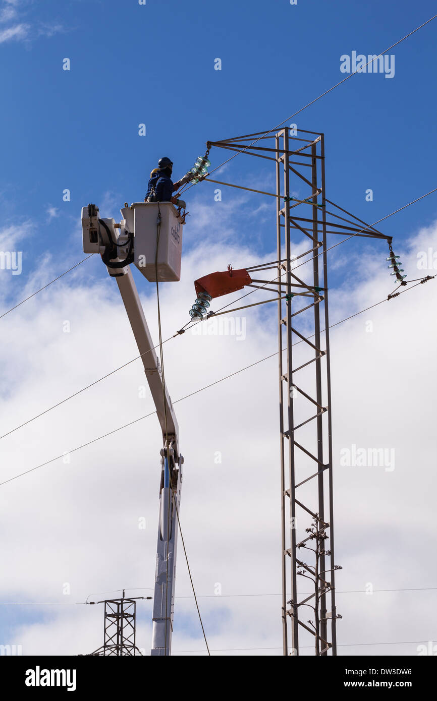 Power workers in a cherry picker working on high tension cables. Stock Photo