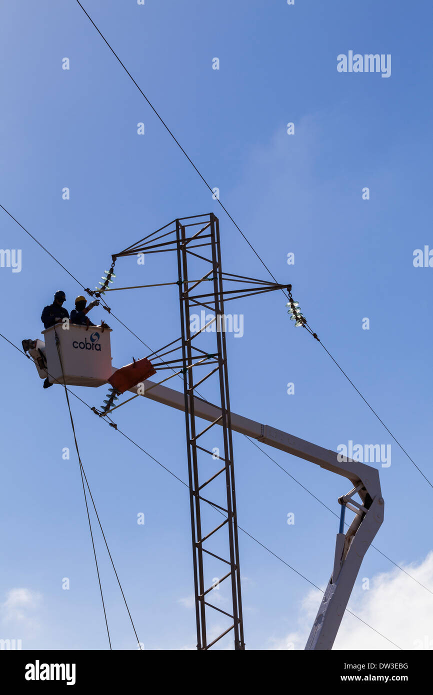 Power workers in a cherry picker working on high tension cables. Stock Photo