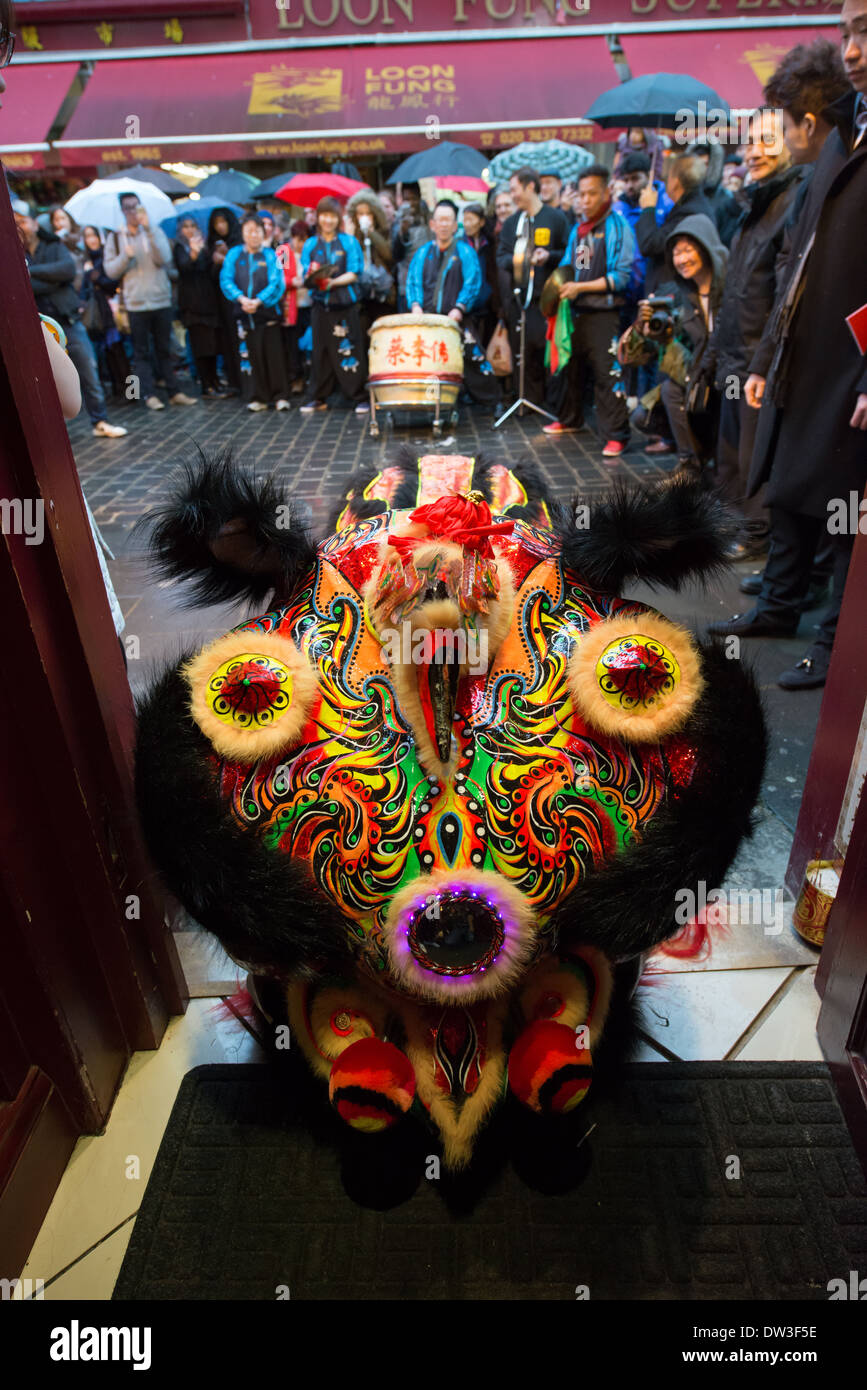 Lion Dancer from the London Chinatown Chinese Association asking for offerings in the doorway of the Feng Shui Inn at Chinese New Year, Gerrard Street, London, England Stock Photo