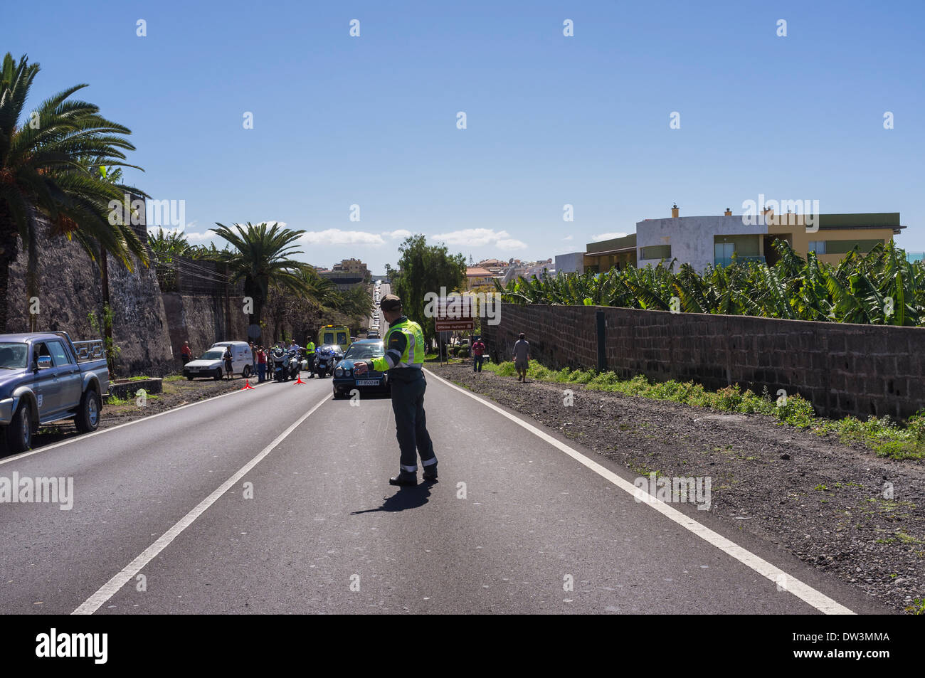 A Guardia Civil Trafico policeman direcing vehicles around the scene of a road traffic accident near Playa San Juan on Tenerife, Stock Photo