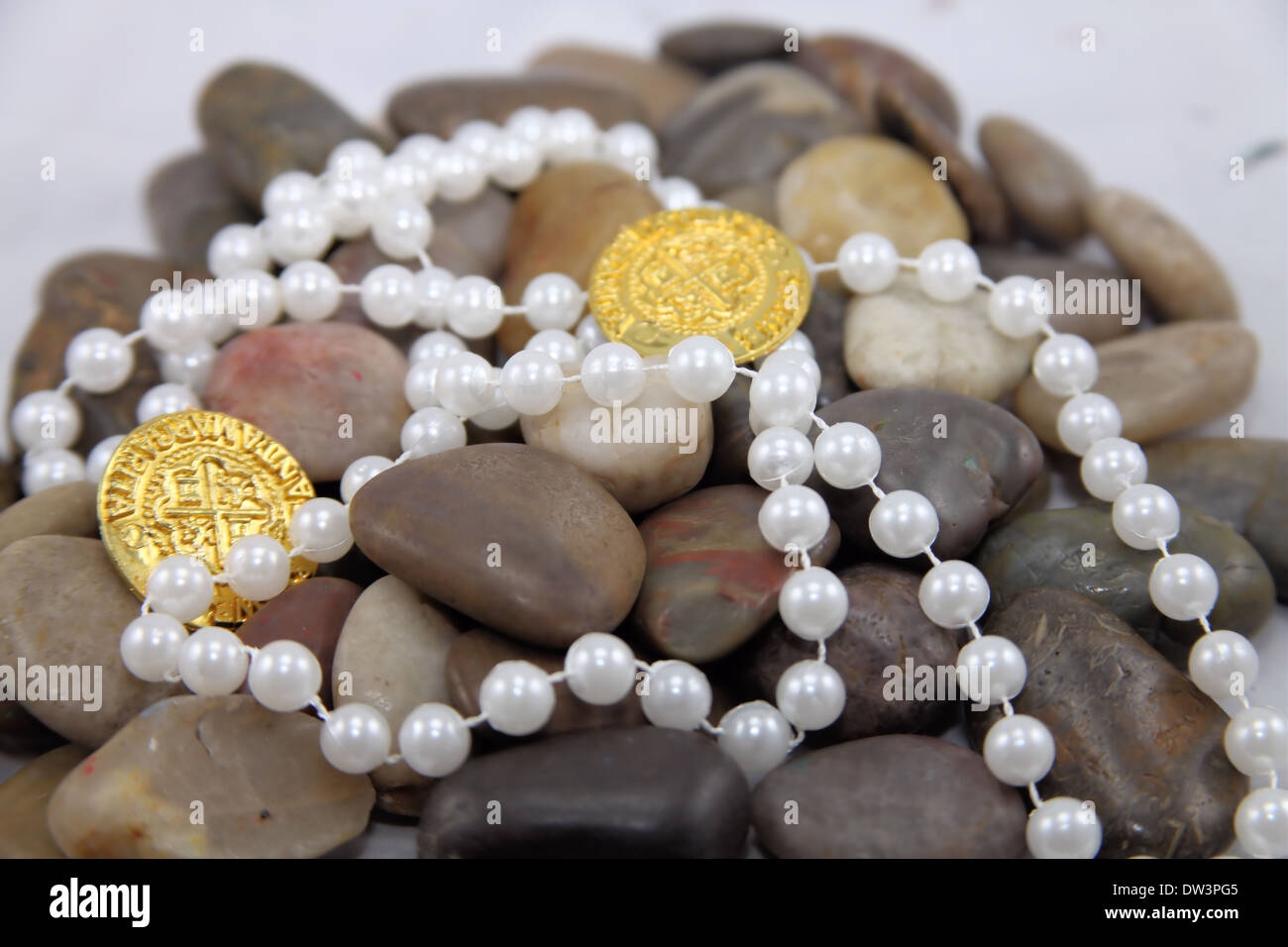 OLD SPANISH GOLD COINS,BEADS ON RIVER ROCKS Stock Photo